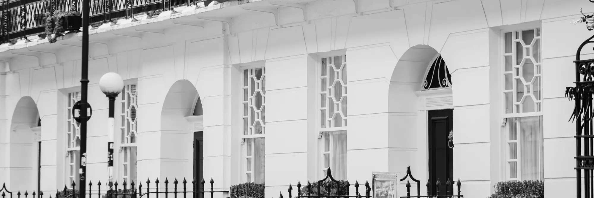 Georgian terraced houses with iron balconies on a London street, in black and white.
